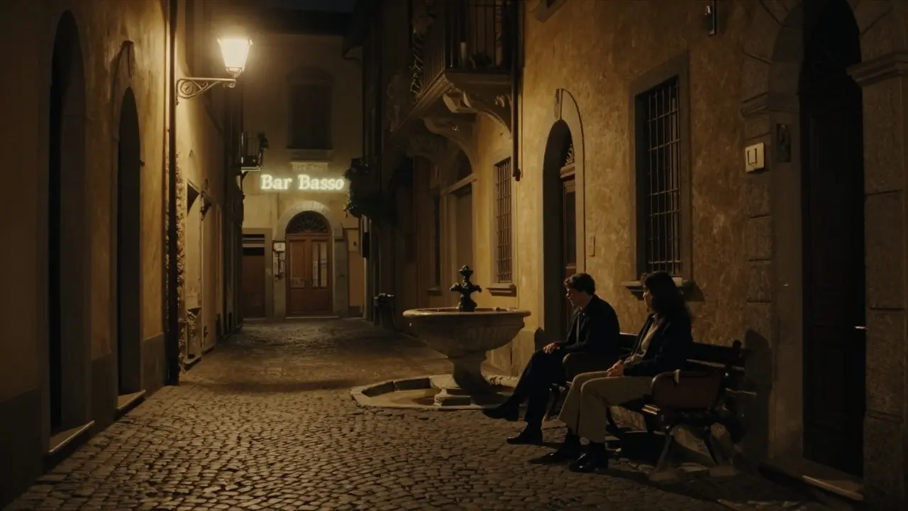 Two people sitting in silent contemplation on a bench beside a fountain in Brera at night.